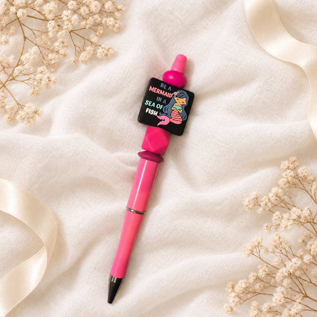 Pinker Kugelschreiber mit Meerjungfrauenmotiv und Perlen in Pink und Beere auf weißem Musselin
